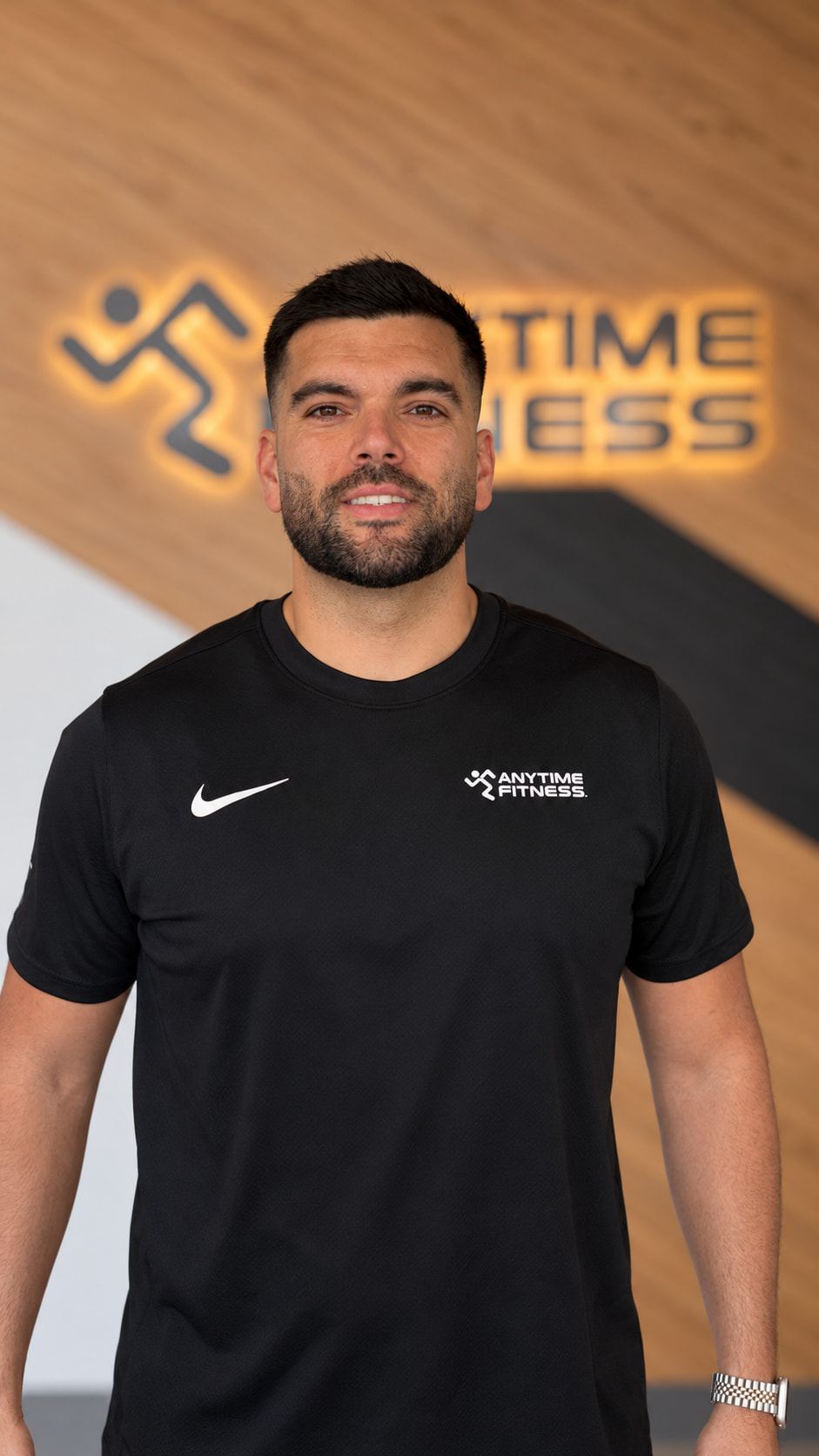 Pablo smiling at the camera in a black T-shirt at Anytime Fitness.